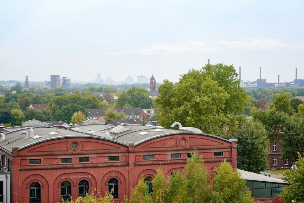 View of the Essen skyline and the Zollverein World Heritage Site. In the foreground, Hall 7 of Triple Z, formerly the hoisting machine house. Picture: Triple Z AG/Yannik Willing